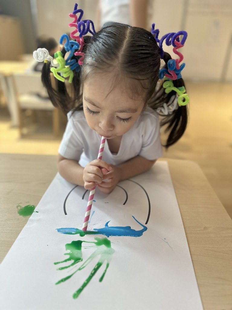 Lenguaje verbal, pequeña soplando a través de una pajilla, en Colegio APDE Connections Cayalá